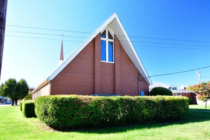 Brick exterior wall of Redeemer with a tall cross window beneath the roof peak