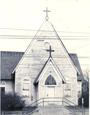 Archival front view of Redeemer's early wooden church building with a cross above the entrance